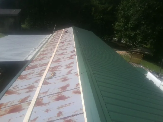 Old rusted panels beside newly installed green metal roofing — Wind Damage Roof Repair by Roofing Brothers in Fremont