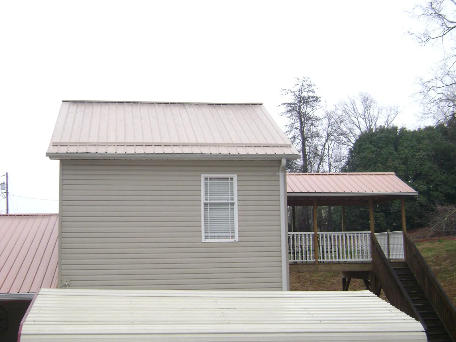 Tan metal roofs on a two story addition and attached porch in Fremont
